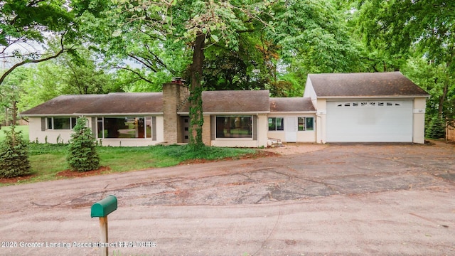 753 E Saginaw St, East Lansing, MI 48823 - ranch-style house with a chimney, driveway, an attached garage, and stucco siding
