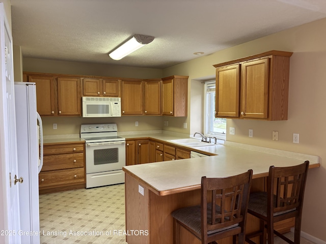 411 White Pine Blvd Unit 34, Lansing, MI 48917 - kitchen featuring white appliances, a peninsula, light countertops, and brown cabinetry