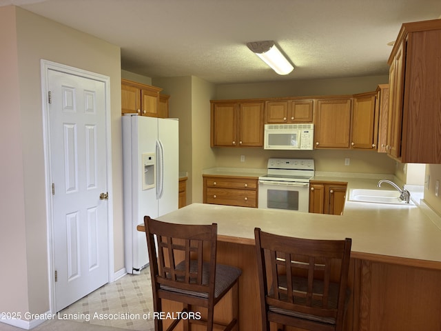 411 White Pine Blvd Unit 34, Lansing, MI 48917 - kitchen with white appliances, light countertops, light floors, a peninsula, and brown cabinets