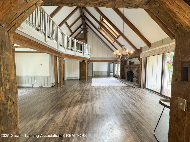 12855 Oneida Woods Trl, Grand Ledge, MI 48837 - unfurnished living room with high vaulted ceiling, a stone fireplace, wood finished floors, a chandelier, and a baseboard radiator