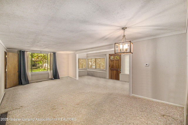 131 W S St, Williamston, MI 48895 - empty room with a textured ceiling, a chandelier, healthy amount of natural light, baseboards, and carpet flooring