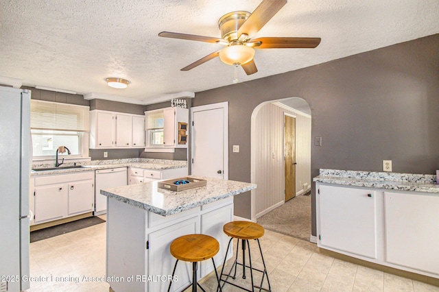 131 W S St, Williamston, MI 48895 - kitchen featuring white appliances, a sink, a textured ceiling, arched walkways, and a kitchen island