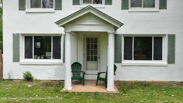 627 State St, Eaton Rapids, MI 48827 - property entrance featuring stucco siding and a yard