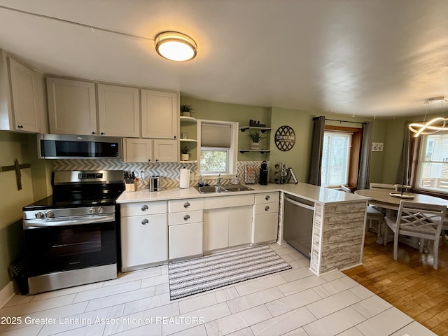 227 S Foster Ave, Lansing, MI 48912 - kitchen featuring appliances with stainless steel finishes, a sink, a peninsula, light countertops, and open shelves