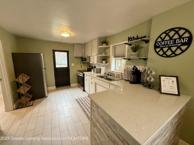 227 S Foster Ave, Lansing, MI 48912 - kitchen with appliances with stainless steel finishes, open shelves, a sink, and white cabinetry
