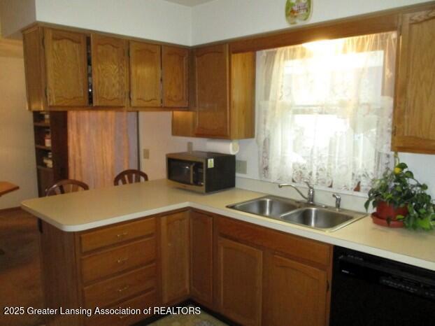 4818 Moultrie Cir, Lansing, MI 48917 - kitchen with black dishwasher, stainless steel microwave, a peninsula, and light countertops