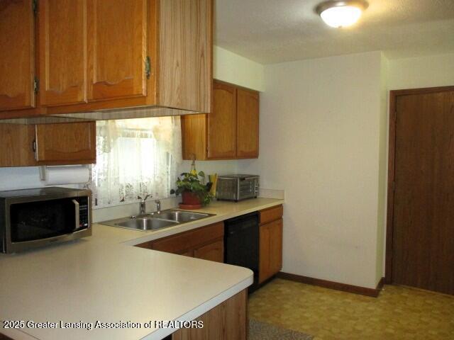 4818 Moultrie Cir, Lansing, MI 48917 - kitchen featuring stainless steel microwave, dishwasher, light countertops, and brown cabinets