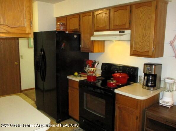 4818 Moultrie Cir, Lansing, MI 48917 - kitchen with black appliances, under cabinet range hood, light countertops, and brown cabinets