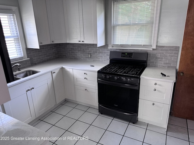 603 Armstrong Rd, Lansing, MI 48911 - kitchen with black gas range oven, tasteful backsplash, white cabinetry, and light tile patterned floors