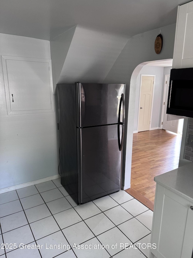 603 Armstrong Rd, Lansing, MI 48911 - kitchen featuring freestanding refrigerator, white cabinets, arched walkways, vaulted ceiling, and light wood-style flooring