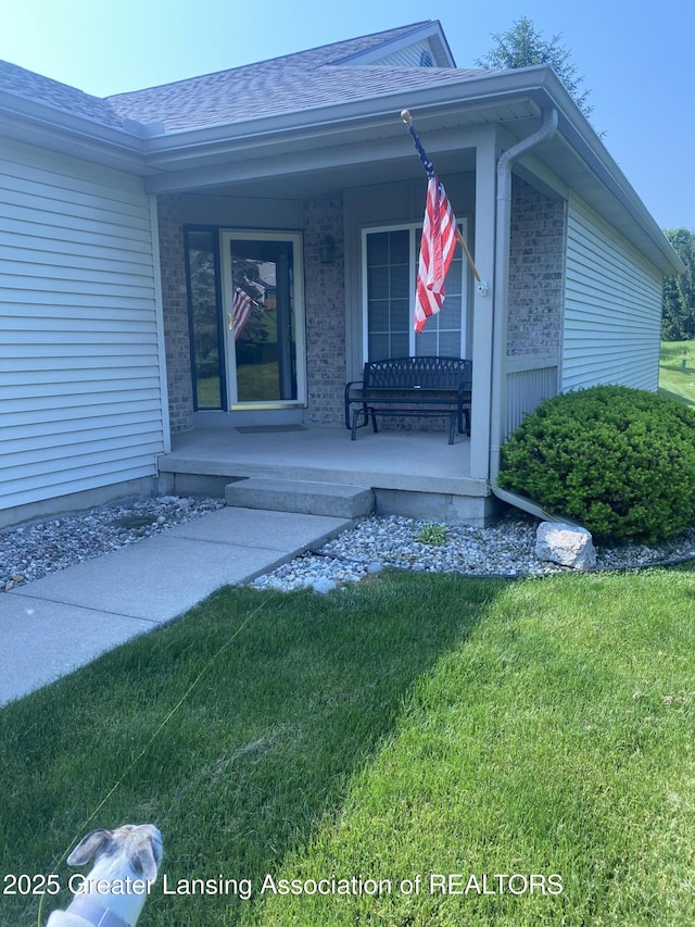 1703 Willow Creek Dr Unit 29, Lansing, MI 48917 - property entrance featuring a porch, a lawn, roof with shingles, and brick siding