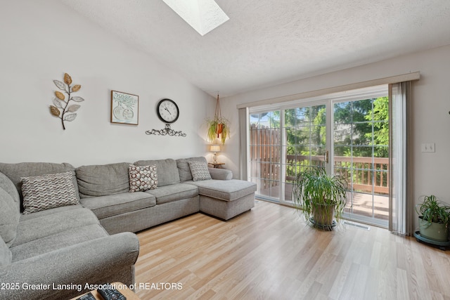 1703 Willow Creek Dr Unit 29, Lansing, MI 48917 - living room featuring a textured ceiling, vaulted ceiling, wood finished floors, and a skylight