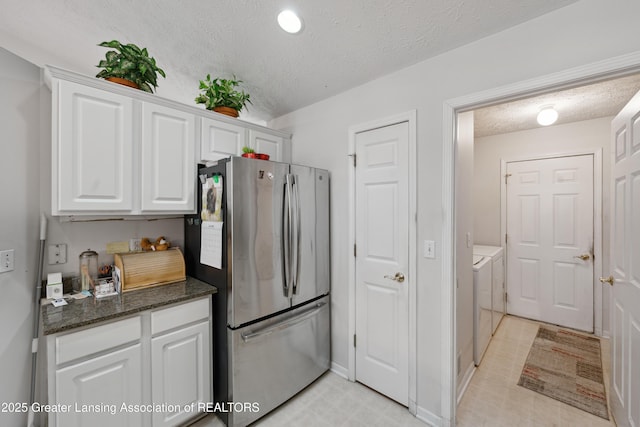 1703 Willow Creek Dr Unit 29, Lansing, MI 48917 - kitchen featuring freestanding refrigerator, a textured ceiling, washer and dryer, white cabinetry, and dark stone countertops