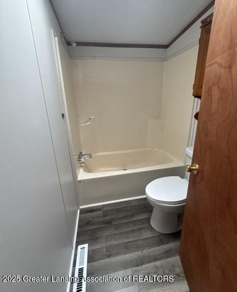 26506 E Baseline Hwy, Charlotte, MI 48813 - bathroom featuring wood finished floors, toilet, and washtub / shower combination