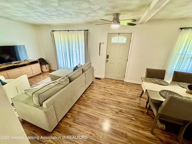 3130 Delta River Dr, Lansing, MI 48906 - living area featuring wood finished floors, a ceiling fan, baseboards, and beamed ceiling