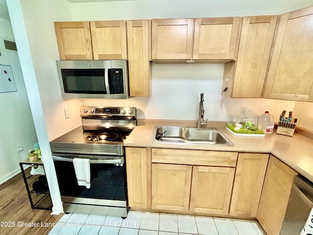 3130 Delta River Dr, Lansing, MI 48906 - kitchen featuring appliances with stainless steel finishes, a sink, light brown cabinets, and light countertops