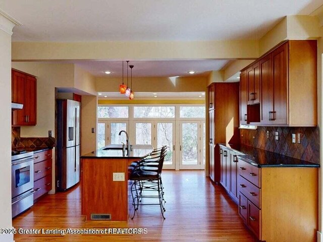 1046 Cresenwood Rd, East Lansing, MI 48823 - kitchen with stainless steel appliances, dark wood-style flooring, dark countertops, a center island with sink, and recessed lighting