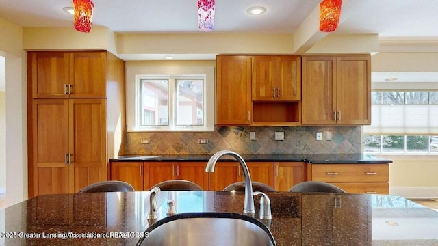 1046 Cresenwood Rd, East Lansing, MI 48823 - kitchen with brown cabinetry, tasteful backsplash, dark stone countertops, recessed lighting, and open shelves
