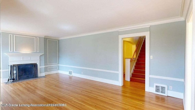 1046 Cresenwood Rd, East Lansing, MI 48823 - unfurnished living room featuring stairway, light wood finished floors, a fireplace, and crown molding