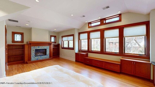 1046 Cresenwood Rd, East Lansing, MI 48823 - unfurnished living room with light wood-type flooring, vaulted ceiling, a glass covered fireplace, and recessed lighting