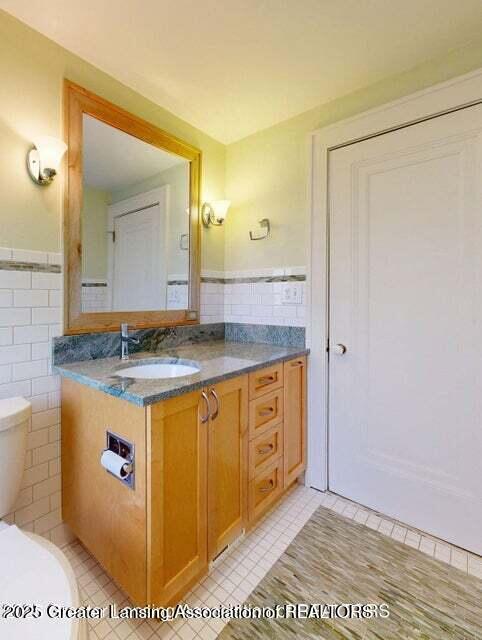 1046 Cresenwood Rd, East Lansing, MI 48823 - bathroom featuring vanity, tile patterned floors, tile walls, and wainscoting