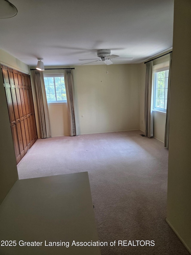 2115 Lyman Dr, Lansing, MI 48912 - empty room featuring healthy amount of natural light, light colored carpet, and ceiling fan