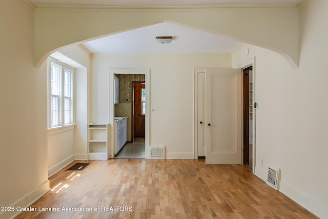 523 N Fairview Ave, Lansing, MI 48912 - empty room featuring arched walkways, light wood finished floors, baseboards, and crown molding