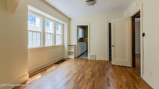 523 N Fairview Ave, Lansing, MI 48912 - unfurnished bedroom featuring wood finished floors, baseboards, and connected bathroom
