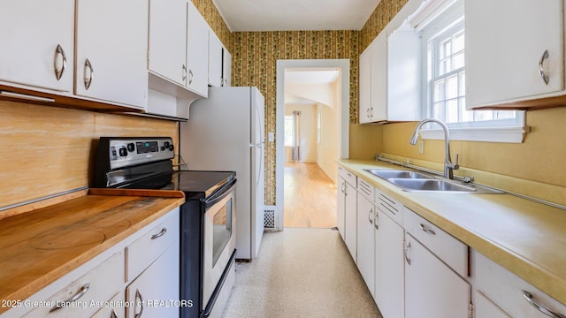 523 N Fairview Ave, Lansing, MI 48912 - kitchen with stainless steel electric range oven, a sink, plenty of natural light, white cabinetry, and wallpapered walls