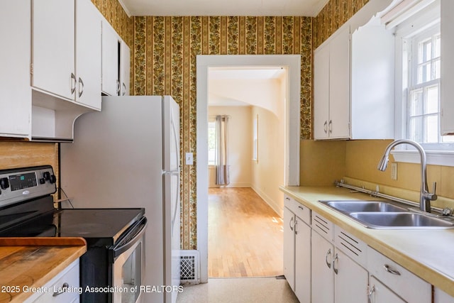 523 N Fairview Ave, Lansing, MI 48912 - kitchen with stainless steel electric range, wallpapered walls, a sink, white cabinets, and light countertops