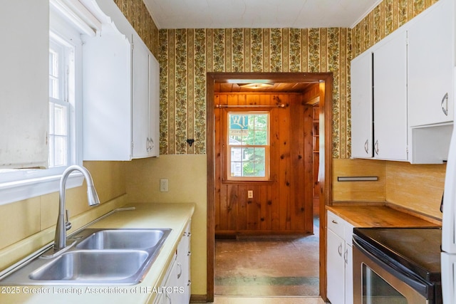 523 N Fairview Ave, Lansing, MI 48912 - kitchen featuring wallpapered walls, a sink, electric stove, white cabinetry, and light countertops