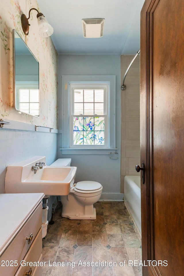 523 N Fairview Ave, Lansing, MI 48912 - full bath with toilet, healthy amount of natural light, bathing tub / shower combination, stone finish flooring, and wallpapered walls