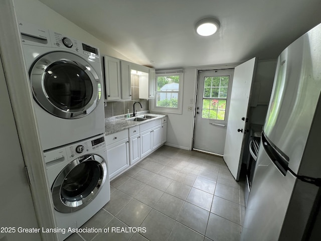 4219 Richmond St, Lansing, MI 48911 - laundry area featuring estacked washer and dryer, light tile patterned floors, and baseboards