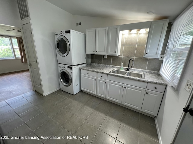 4219 Richmond St, Lansing, MI 48911 - washroom with stacked washer / dryer, cabinet space, tile patterned floors, and baseboards