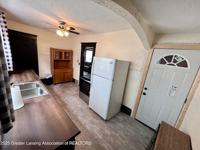 1403 W Michigan Ave, Lansing, MI 48915 - kitchen featuring freestanding refrigerator, a textured ceiling, a sink, ceiling fan, and light wood-type flooring