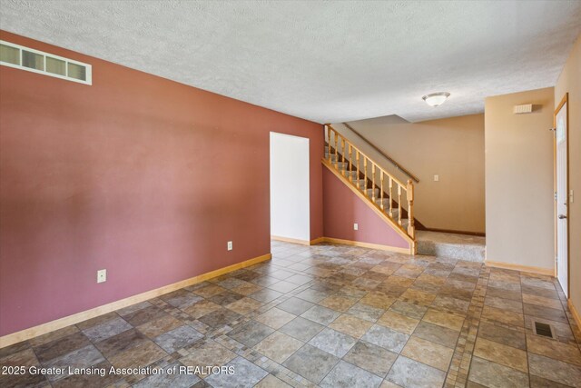 202 Kerry St, Eaton Rapids, MI 48827 - spare room with stairway, stone tile floors, and a textured ceiling
