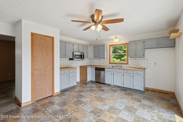 202 Kerry St, Eaton Rapids, MI 48827 - kitchen featuring appliances with stainless steel finishes, light stone finish flooring, and gray cabinets