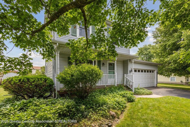 202 Kerry St, Eaton Rapids, MI 48827 - view of front of home featuring a porch, asphalt driveway, an attached garage, and a front lawn