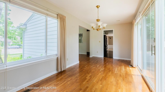 1965 Rutgers Cir, East Lansing, MI 48823 - unfurnished dining area featuring a chandelier, light wood finished floors, and healthy amount of natural light