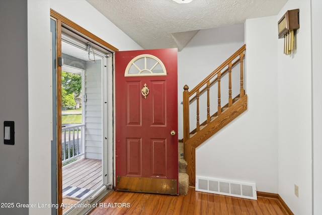921 Ives Rd, Mason, MI 48854 - foyer with stairs, wood finished floors, and a textured ceiling