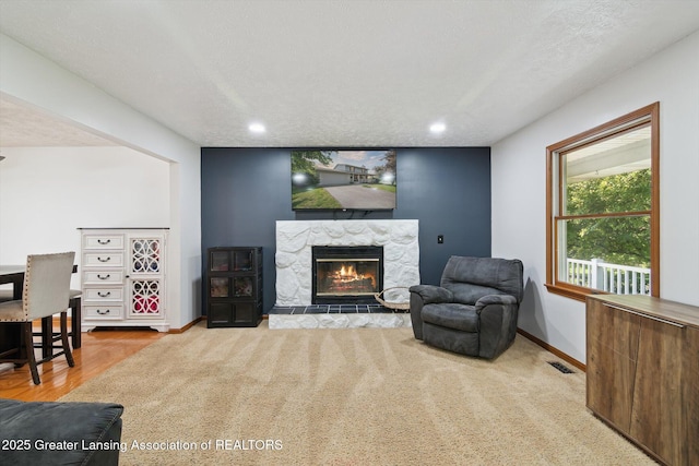 921 Ives Rd, Mason, MI 48854 - living area featuring a stone fireplace, recessed lighting, baseboards, a textured ceiling, and wood finished floors