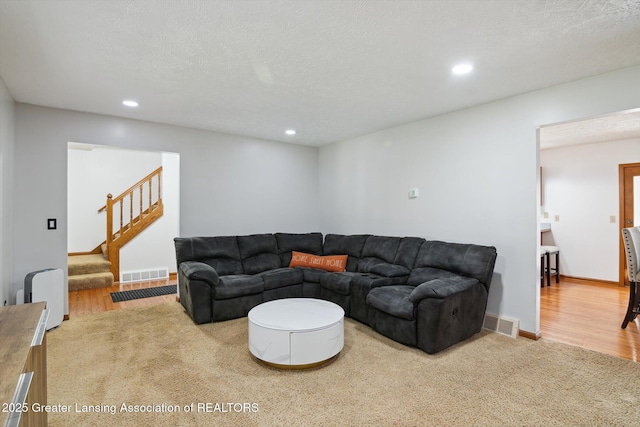 921 Ives Rd, Mason, MI 48854 - living room with carpet floors, stairs, recessed lighting, a textured ceiling, and wood finished floors