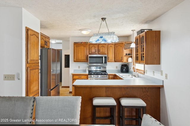 921 Ives Rd, Mason, MI 48854 - kitchen with appliances with stainless steel finishes, a sink, a peninsula, brown cabinets, and light countertops
