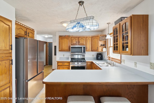921 Ives Rd, Mason, MI 48854 - kitchen with appliances with stainless steel finishes, a peninsula, light countertops, glass insert cabinets, and brown cabinetry