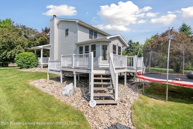 921 Ives Rd, Mason, MI 48854 - back of house with a trampoline, a deck, a lawn, and a chimney