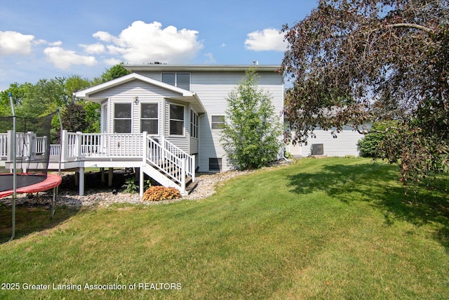 921 Ives Rd, Mason, MI 48854 - back of house with a trampoline, a wooden deck, and a lawn