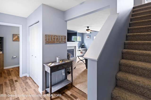 15925 Turnberry St, Lansing, MI 48906 - stairs with wood finished floors, a ceiling fan, and a fireplace