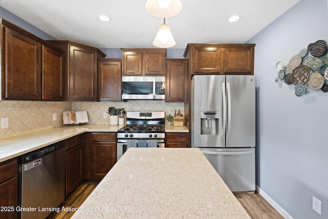 15925 Turnberry St, Lansing, MI 48906 - kitchen featuring appliances with stainless steel finishes, wood finished floors, decorative backsplash, recessed lighting, and hanging light fixtures