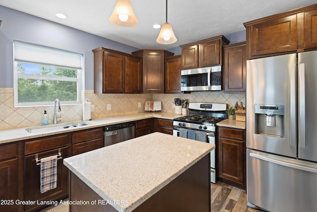 15925 Turnberry St, Lansing, MI 48906 - kitchen with stainless steel appliances, wood finished floors, a kitchen island, hanging light fixtures, and backsplash