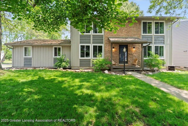 992 Touraine Ave, East Lansing, MI 48823 - view of front of home with a front yard, board and batten siding, and brick siding